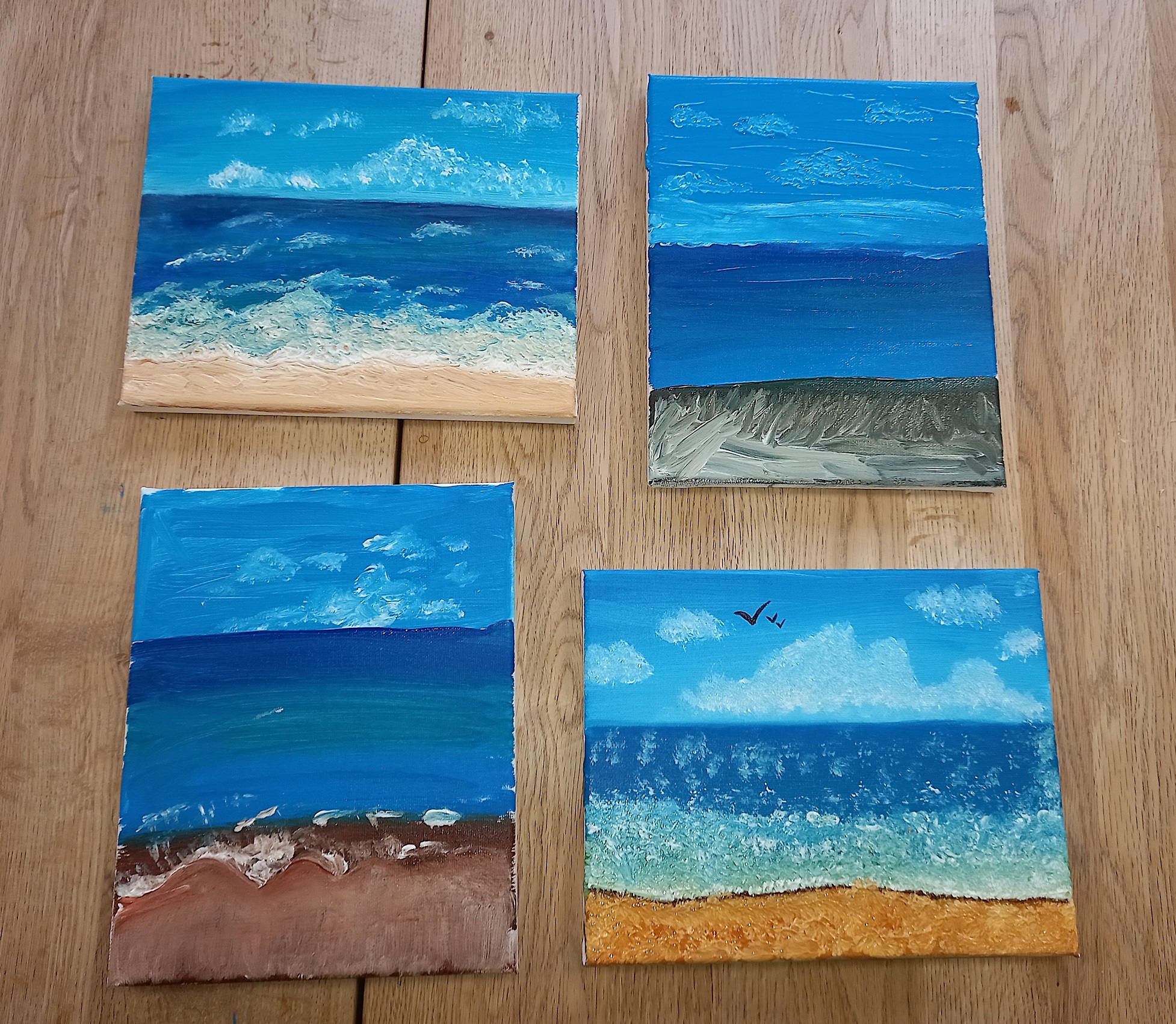 Four lovely paintings, all unique but containing the sky, sea, and the coast or beach.