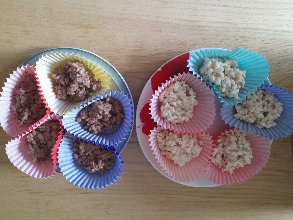 Two plates of tasty rice crispie cakes, made by a customer in a keywork session. They are brown and white and in colourful cake cases.