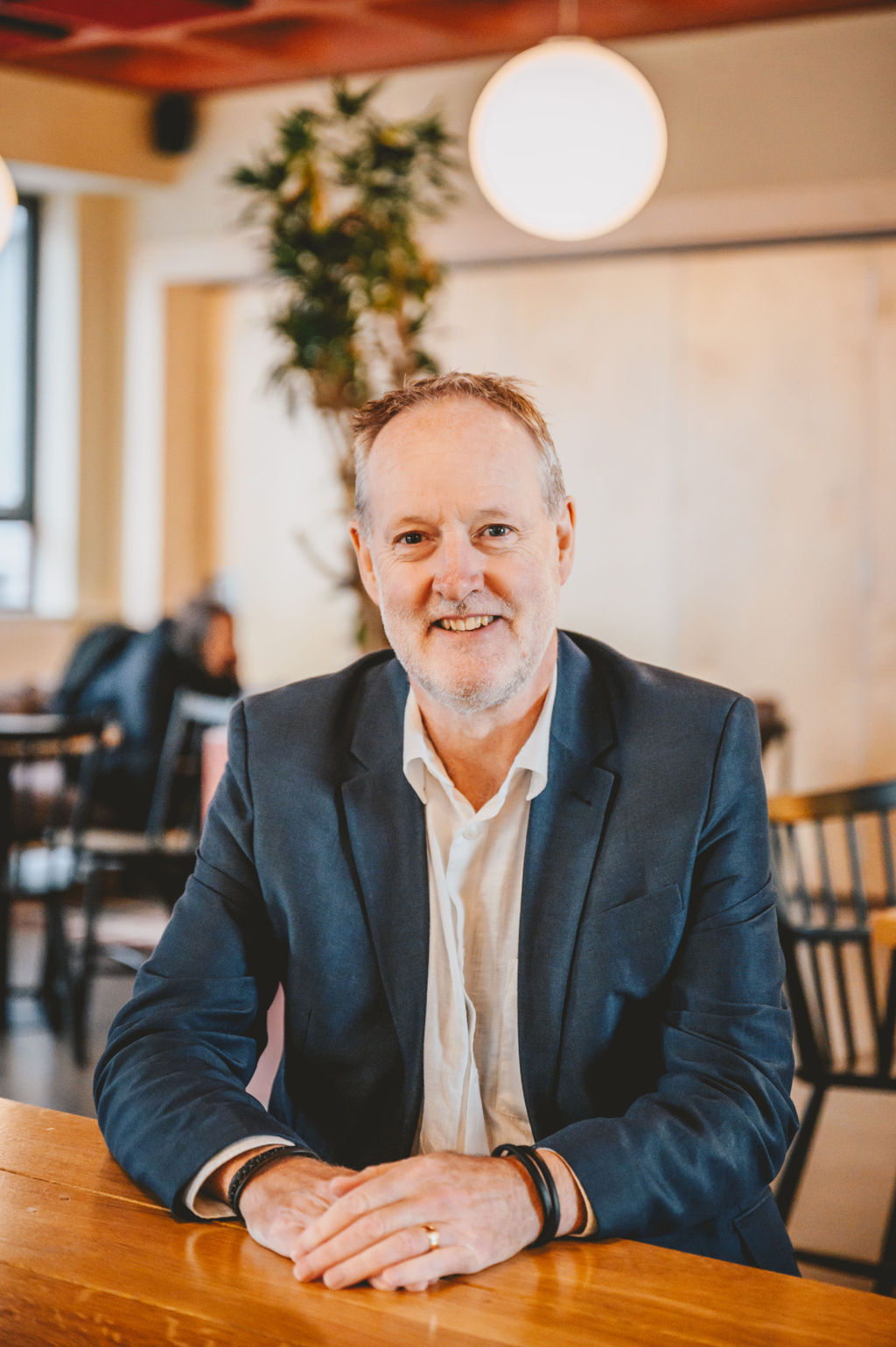 A photo of Matt Harrison, our Chair of the Board. He is sat at a table and smiling at the camera.