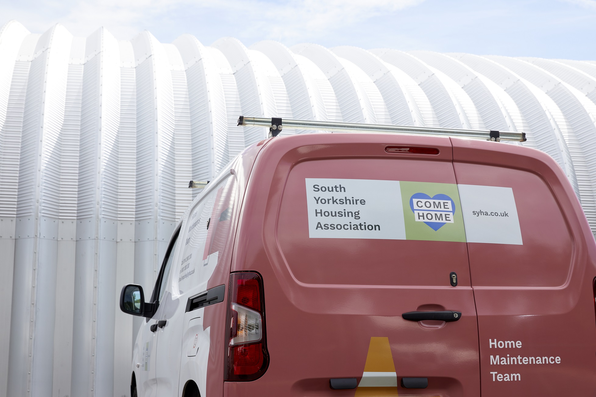 A photo of one our maintenance vans at the depot. It is pink and white, with our logo and an illustration of a traffic cone on the back.